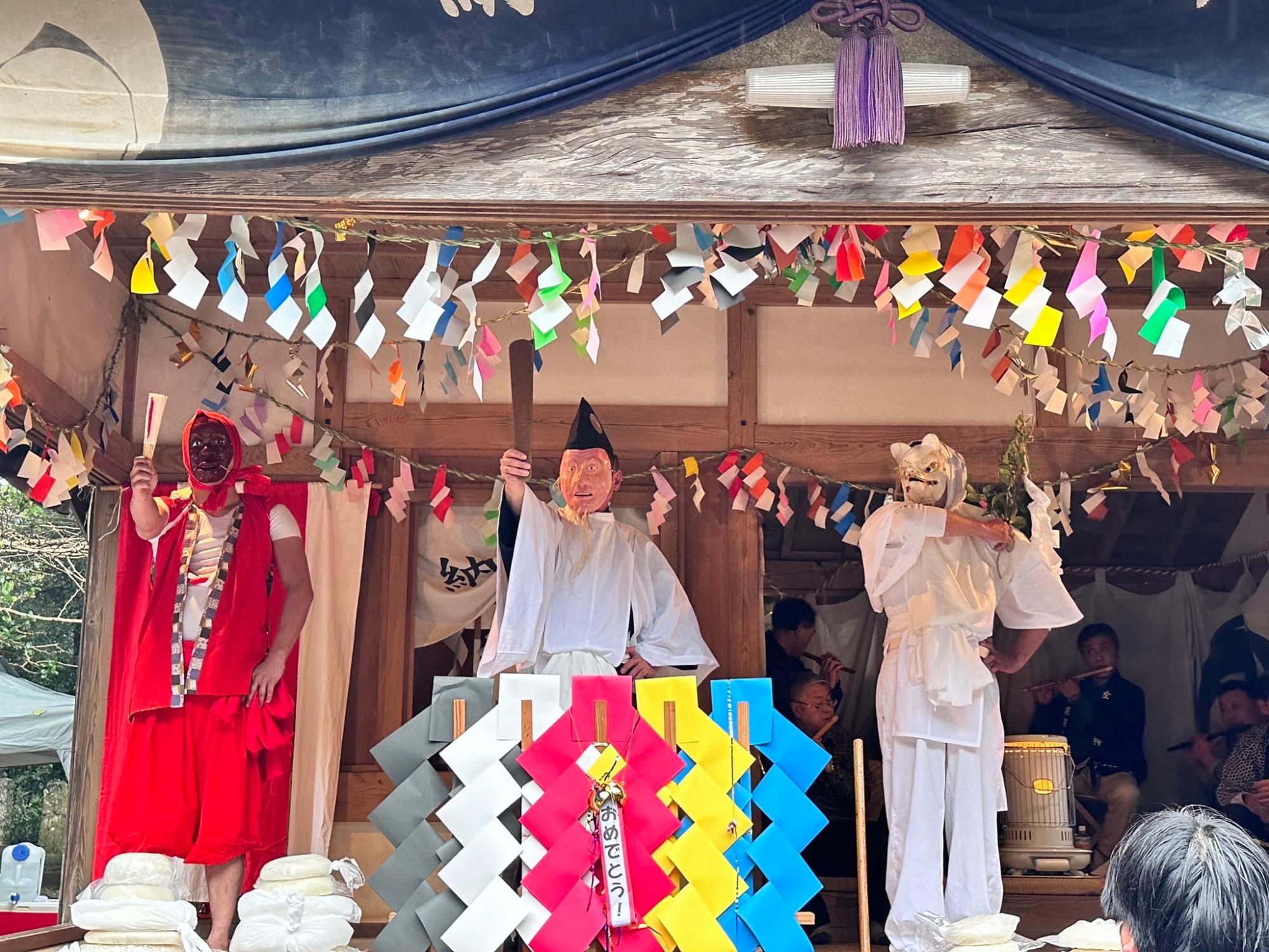 稲荷様(いなりさま)、きつね(きつね)、種蒔(たねまき)の演者が神楽殿に並んでいる写真