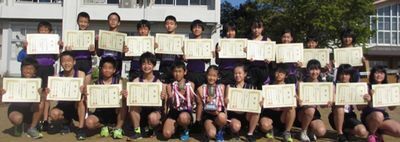 前列の中央の2名がトロフィーを持ち、それ以外の前列と後列の選手が賞状を持っている陸上部員の集合写真