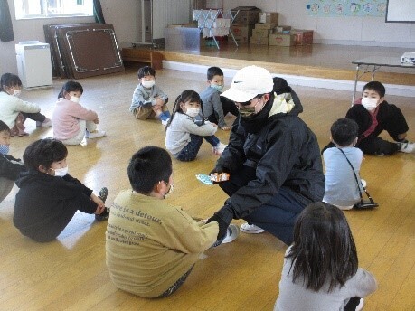 不審者役の女性が男の子に話しかけているのを周りの子ども達が見ている写真