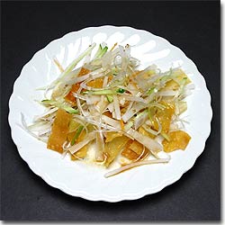 白いお皿に、長ネギやきゅうり、ワンタンの皮を揚げたものを絡めた中華風サラダを盛り付けた写真