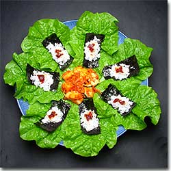 青色の器に敷いたサンチュの上に白飯とコチジャンがのった味付け海苔と白菜キムチが盛り付けられた写真