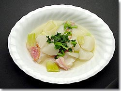 白い深皿にこかぶ、ベーコン、玉ねぎなどが盛り付けられたこかぶと葱のスープ煮の写真