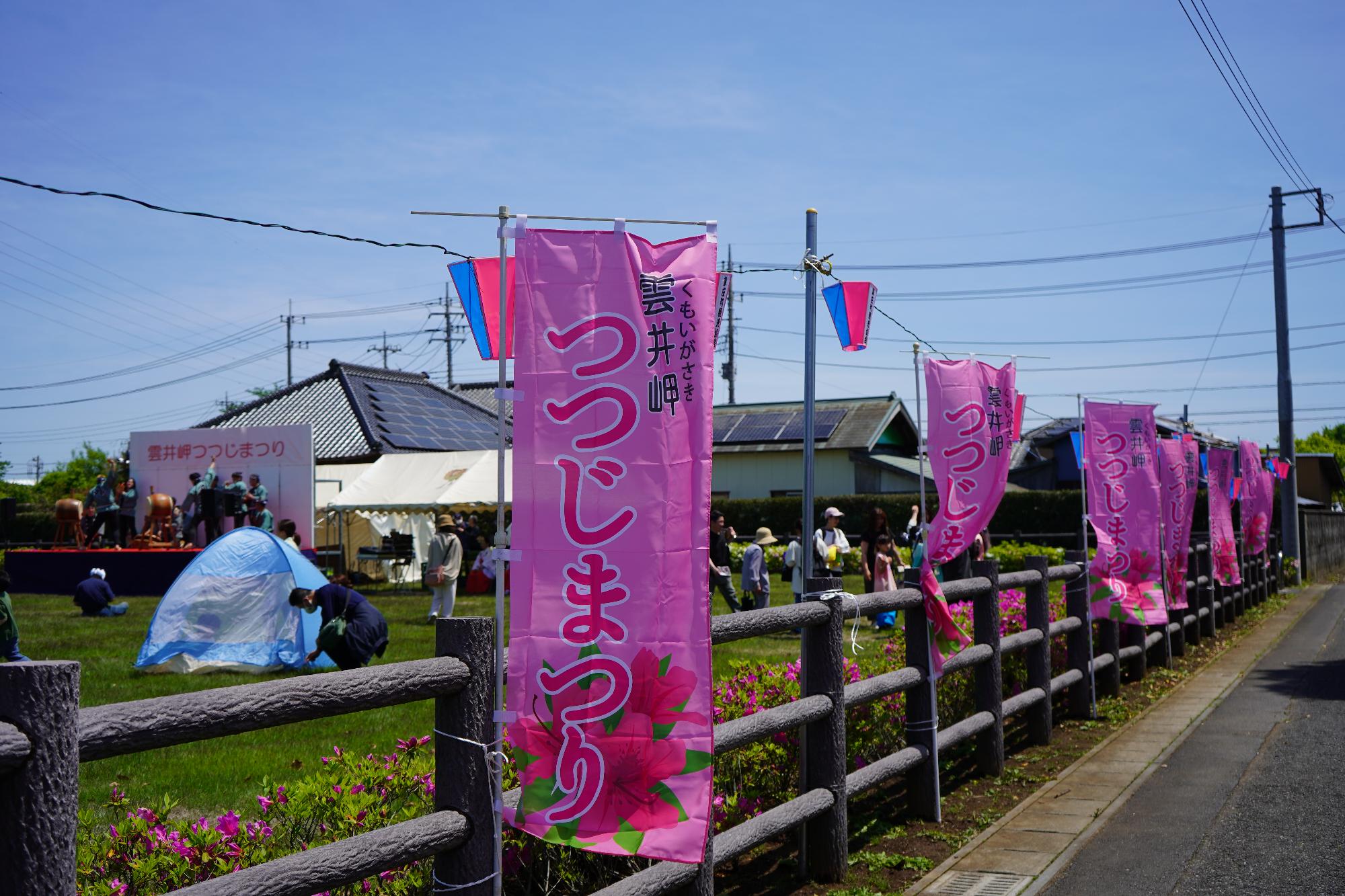 雲井岬つつじまつりのピンク色ののぼりが並ぶステージ脇の道