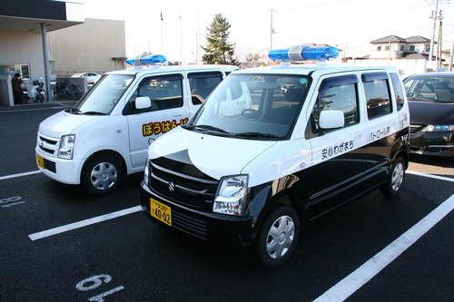 あんしんわがまちパトロール隊の車2台が駐車場に停まっている写真