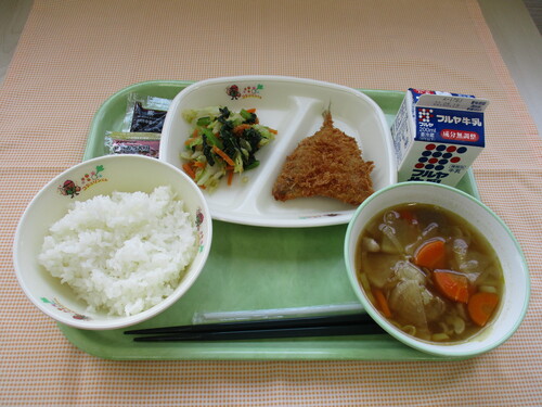 左手前から反時計周りにごはん、けんちん汁、その奥に牛乳、あじフライ、ごま和えがトレーに並べられた写真