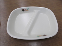 仕切りの付いたお皿の左右にコジュリンくんのイラストが入っている給食食器の写真